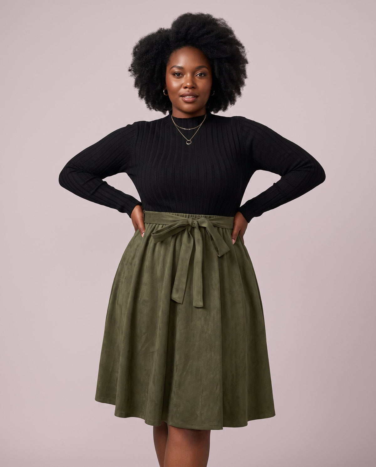 Black woman wearing a black and olive green midi dress with long sleeves and flare skirt