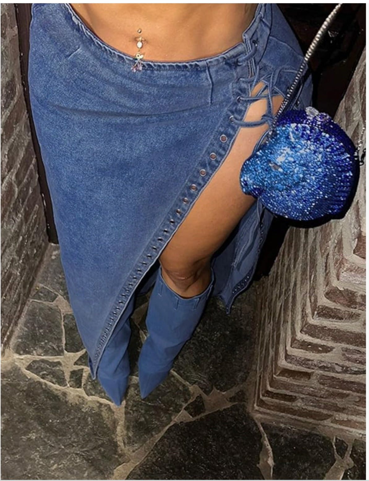 Back view of a woman wearing a blue denim maxi skirt with a high side slit and flowing maxi-length design, showcasing the stylish fit and dramatic silhouette.