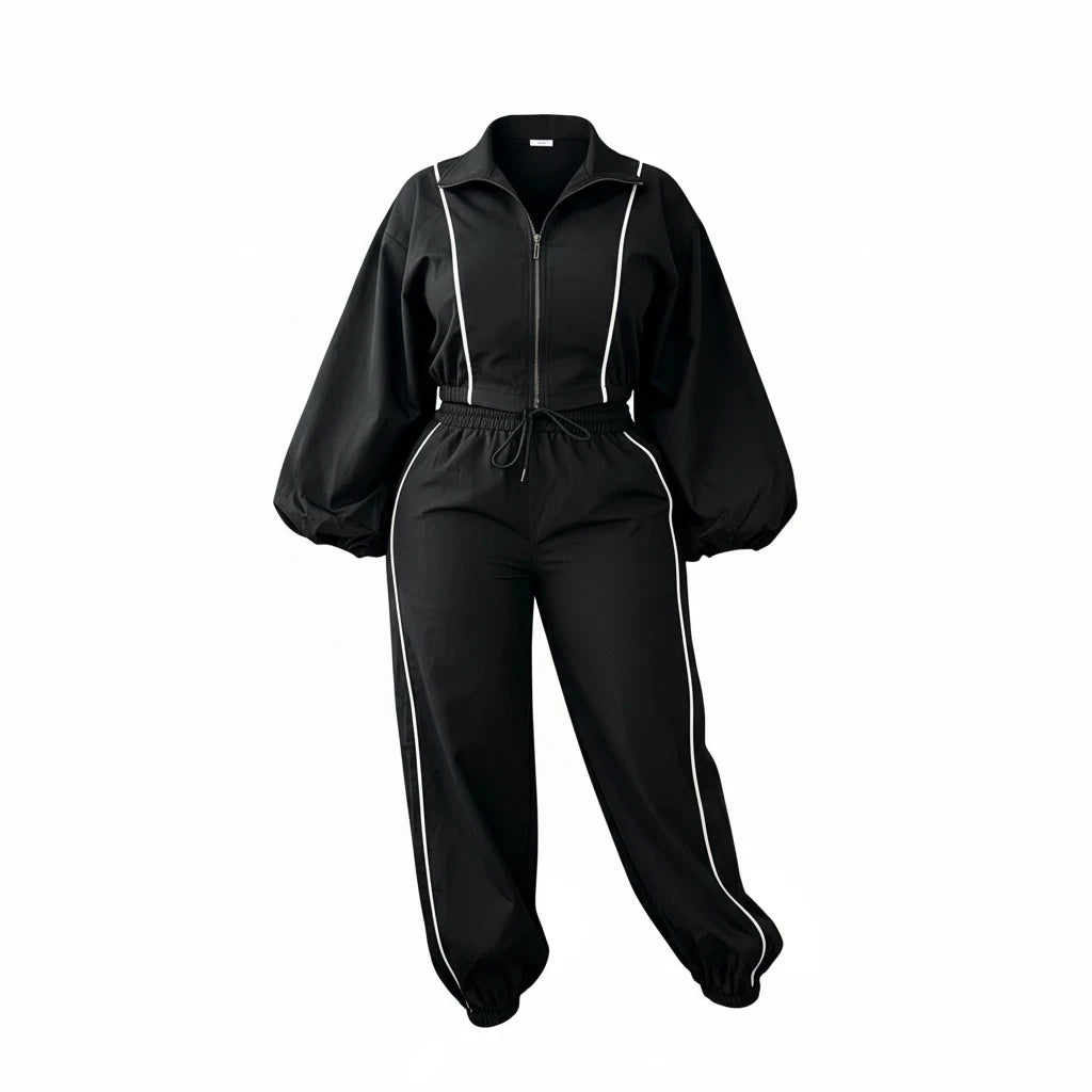 Swerves & Curves Boutique black two-piece jogger set with cropped zip-up jacket, puff sleeves, and white piping detail.