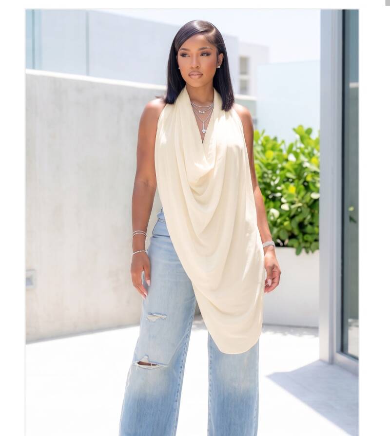 Swerves & Curves Boutique cream sheer halter top with a draped cowl neckline worn by a woman with blue jeans