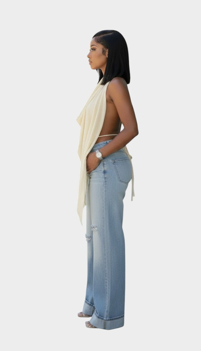 Swerves & Curves Boutique cream sheer cowl neck halter top with open back worn by a model with light wash denim jeans