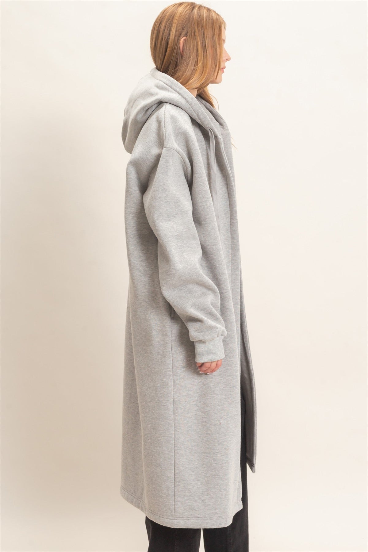 Side view of a woman wearing a Swerves & Curves Boutique gray longline hooded jacket in soft knit fabric.